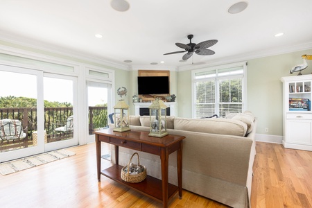 Gather with friends and family in this airy living area featuring a flat-screen TV, hardwood floors, and beach-inspired décor.