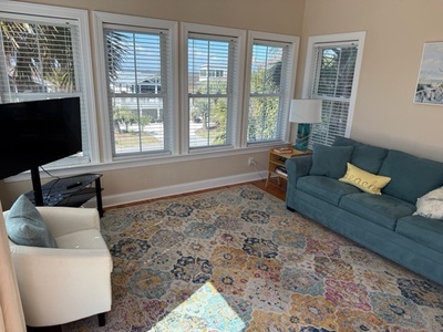 Relax in your bright living room with panoramic windows showcasing tropical palm views and distant ocean glimpses.