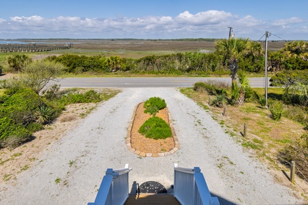 Elevated view showcasing the property's entrance driveway with coastal marshland and natural vegetation in the background.