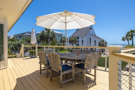 Dine al fresco under the umbrella with views of the pool and the ocean beyond