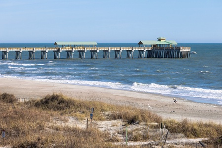 A scenic coastal pier extends into the Atlantic, offering a glimpse of the natural beauty and recreational charm of the surrounding beachfront area.