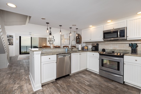 Your fully equipped kitchen features granite countertops, stainless steel appliances, and warm pendant lighting—perfect for preparing meals together.