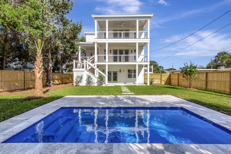 Modern three-story beach house with pristine pool and tropical landscaping in a peaceful residential setting.