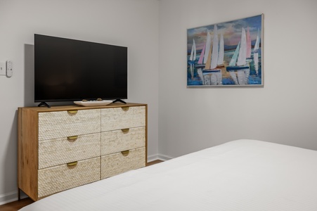 Unwind in your serene bedroom where coastal artwork and modern amenities create the perfect retreat after exploring.