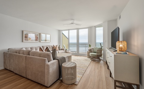 Sink into plush sofas while ocean waves frame your panoramic balcony view in this airy living space.