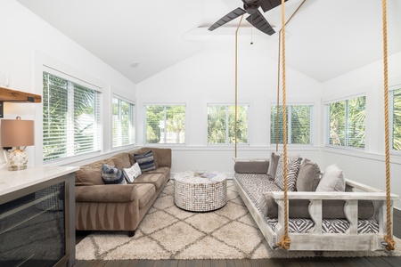 This sunroom features an abundance of natural light, a wet bar, and a cozy rope swing