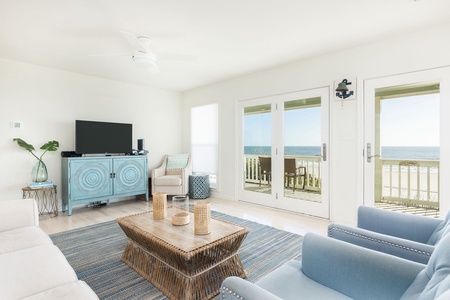Spacious coastal-inspired living room with large windows overlooking the beach