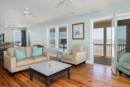 Unwind in your airy coastal living room with ocean views. Gentle breezes flow through open doors while you relax on plush seating.