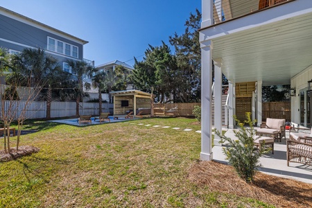 Spacious backyard with covered patio seating where you can relax while kids play on the lawn and explore the charming wooden playhouse.