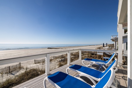 Relax on your private deck with stunning ocean views. Three blue loungers await as you soak in the endless beach panorama.
