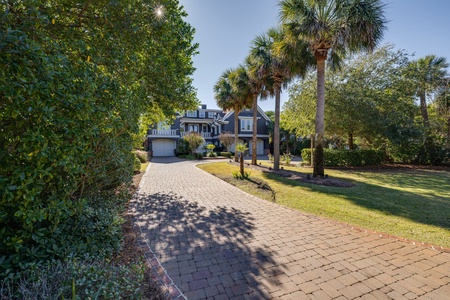 The driveway leads through lush tropical landscaping and towering palms