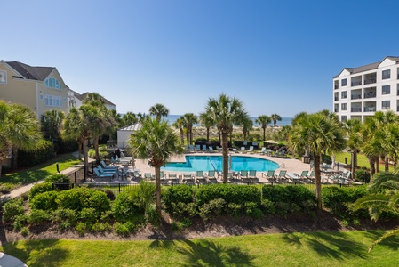 Coastal resort with outdoor pool, palm-lined grounds, and ocean views just steps from the beach, framed by residential buildings and tropical landscaping.