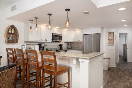 Your fully equipped kitchen features granite countertops, stainless steel appliances, and warm pendant lighting—perfect for preparing meals together.
