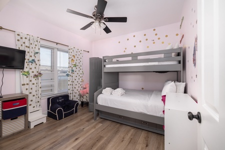 Your kids will love this whimsical bedroom featuring a cozy bunk bed, playful polka dot decor, and entertainment space for magical bedtime stories.