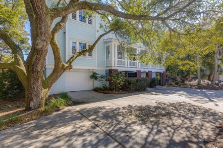 Charming coastal-style home nestled under mature oak trees with spacious driveway and landscaped grounds