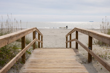 Private boardwalk leads through coastal dunes to beach.