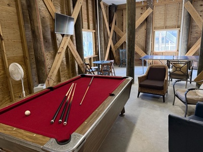 Your personal game room awaits with a vibrant red pool table surrounded by rustic wooden beams and comfortable seating where you can unwind.