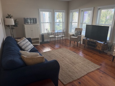 Relax in your bright living space with gleaming hardwood floors, comfortable seating, and natural light streaming through bay windows.