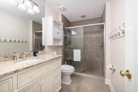 This bright, elegant bathroom features a spacious walk-in shower with rainfall head, classic white vanity with elegant granite countertops, and clean modern finishes that create your perfect retreat after a day exploring nearby beaches.
