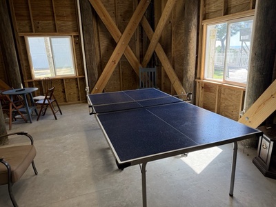 Challenge friends to ping pong matches in your own rustic game room, complete with exposed beams and natural light streaming through windows.