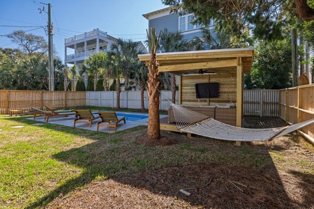 Private backyard oasis with swimming pool, loungers, hammock, and outdoor entertainment area perfect for relaxation.