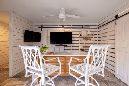 Sliding barn doors and whitewashed shiplap lend coastal character to the outdoor bar