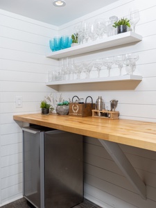 Your personal wet bar awaits with sleek floating shelves, butcher block counter, and mini fridge for evening cocktails.