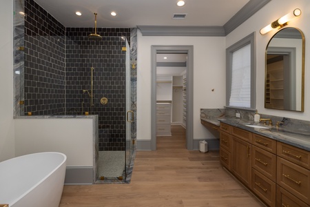 Indulge in your private spa-like bathroom featuring a sleek soaking tub, rainfall shower, and elegant marble countertops.