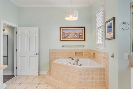 Unwind in your serene spa-style bathroom featuring a luxurious soaking tub and coastal artwork that creates the perfect retreat.