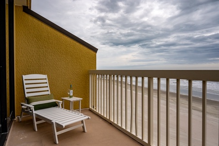 Relax on your private oceanfront balcony with beach chair and side table, watching waves roll onto sandy shores.