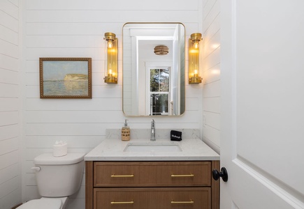 Step into your elegant bathroom featuring warm brass fixtures and coastal artwork that create a serene, spa-like atmosphere.