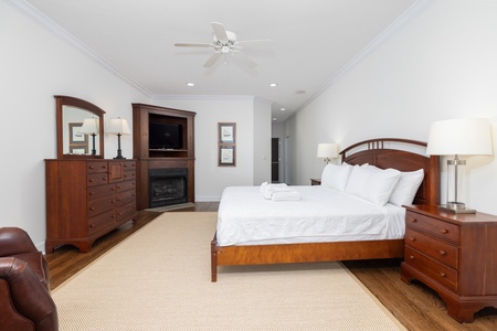 Your spacious bedroom features a plush king bed with premium linens, warm wood furnishings, a cozy fireplace, flat-screen TV, and soft lighting—your perfect retreat after a day of adventure.