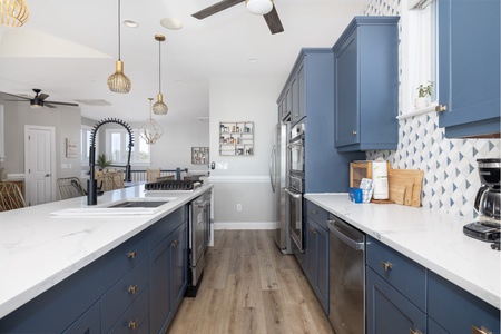 Your spacious kitchen invites culinary adventures with stunning blue cabinetry, gleaming quartz countertops, and modern appliances ready for your favorite recipes.