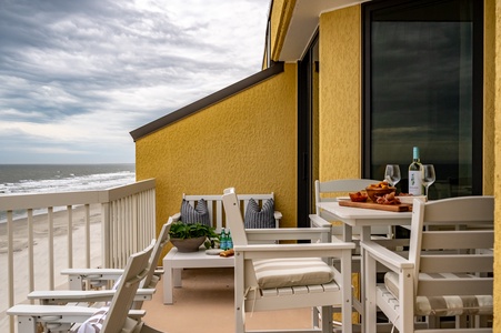 Savor wine and oceanfront dining on your private balcony, where white furniture frames endless sea views.