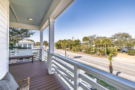 A covered porch with street views, surrounded by palm trees and neighboring homes in a peaceful residential area.