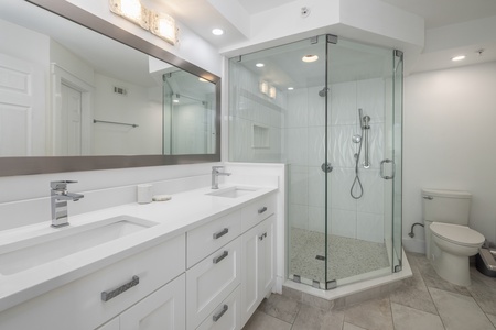 The primary en suite features a glass walk-in shower and dual vanities