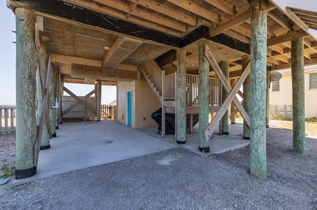 Elevated beach house provides convenient covered parking underneath with sturdy wooden construction.
