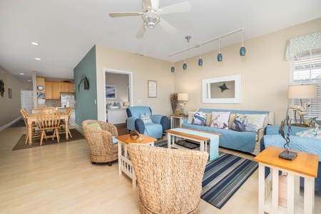 Relax in this coastal-themed living space with comfortable seating, ceiling fan, and open layout connecting to your kitchen and dining area.