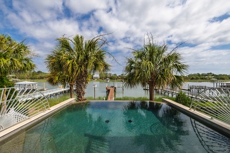 Stunning private pool overlooking serene waterfront vistas, framed by swaying palms and direct dock access—your perfect coastal retreat.