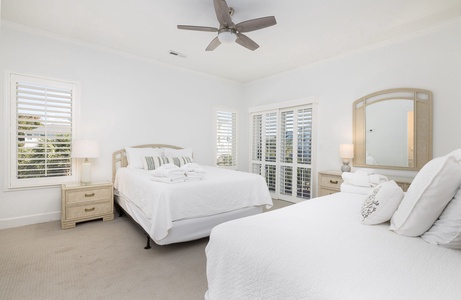Bright downstairs bedroom with a queen and twin beds and large windows for natural light