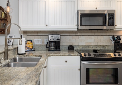 Your fully equipped kitchen features granite countertops, stainless steel appliances, and warm pendant lighting—perfect for preparing meals together.