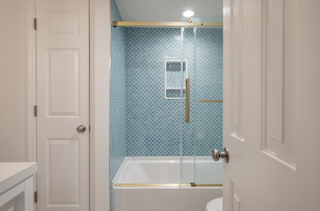 Unwind in your elegant bathroom featuring a deep soaking tub and stunning blue tile work that creates a spa-like retreat.
