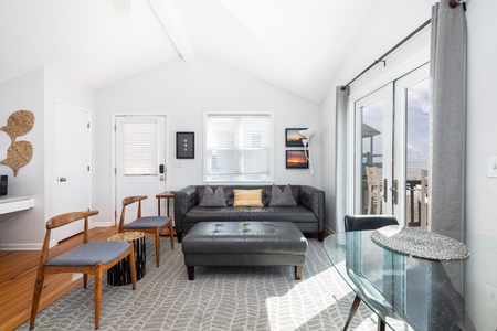 Step into your bright living room with vaulted ceilings and stylish leather seating. Glass doors open to a balcony, inviting you to unwind and soak in the outdoor views.