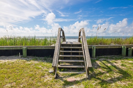 A sunny day near the property showcases coastal charm with easy beach access and natural dune grasses framing ocean views under brilliant blue skies.