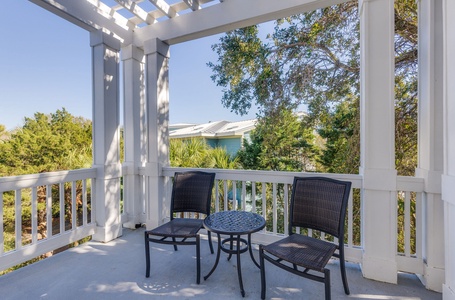 Sip your morning coffee on the primary bedroom balcony under a wooden pergola