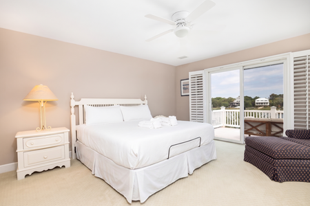 Sink into crisp linens and gentle breezes in your serene bedroom retreat. White wood furniture and soft coastal tones create a peaceful haven, while your private balcony invites you to unwind overlooking tranquil water views.