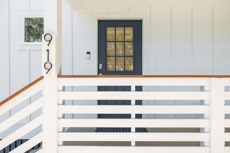 Modern entrance to 919 features clean design elements, welcoming you with a sleek glass-paned door and stylish horizontal railing that frames the covered porch perfectly.