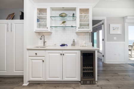 Your wet bar features subway tile backsplash and a wine fridge