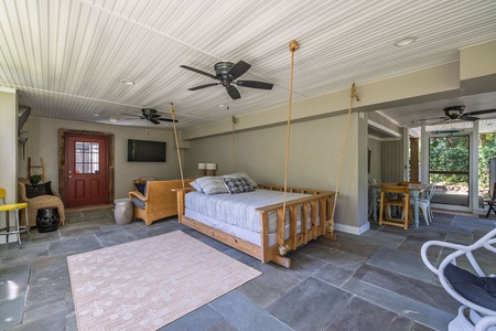 Screened porch with couch, TV, and bed swing