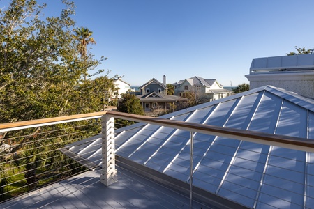 Modern deck with sleek cable railings showcases peaceful neighborhood views and lush greenery beyond.